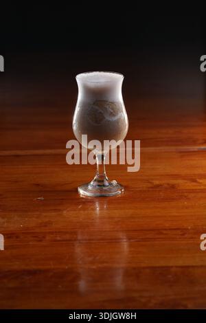 Gekühltes Getränk auf Kaffeebasis mit schaumiger Oberseite, serviert in einem Glas mit Stielstiele, das die cremige Textur und die Eiszubereitung hervorhebt. Stockfoto