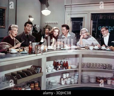 Dieses Farbfoto aus dem Jahr 1953 zeigt eine lebhafte Diner-Szene mit prominenten Darstellern aus dem Film „How to Marry a Millionaire“. Betty Grable, Lauren Bacall und Marilyn Monroe sitzen zusammen mit männlichen Co-Stars an einer Theke, die alle in einem humorvollen und ausdrucksstarken Moment verwickelt sind. Das Ambiente erinnert an eine klassische amerikanische Diner-Atmosphäre aus den 1950er Jahren. Stockfoto