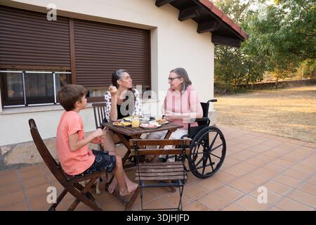 Familienmitglieder mit mehreren Generationen, die im Freien essen und sich auf der Terrasse unterhalten Stockfoto