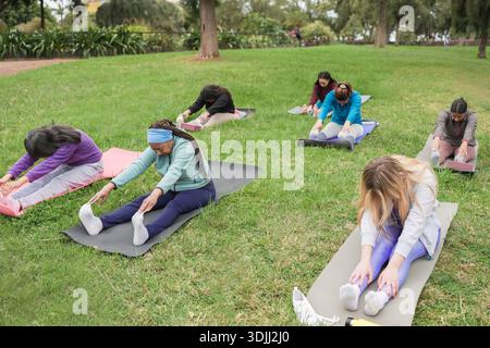 Generationenübergreifende Frauen, die im Stadtpark im Freien Yoga-Übungen machen - gesundes Lebensstil und Sportkonzept - Schwerpunkt auf afrikanischem Seniorengesicht Stockfoto