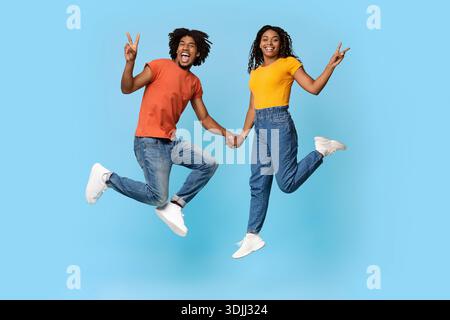 Glückliche afroamerikanische Liebhaber gestikulieren auf Blau Stockfoto