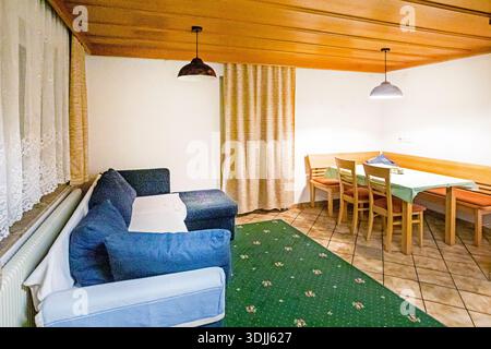 Gemütliche Kochnische mit Holztisch und Sofa gegenüber. Stockfoto