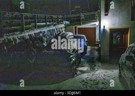 Autos auf einem schneebedeckten Parkplatz nachts auf einer Bergstraße Eis auf der Windschutzscheibe eines Autos. Schlechte Sicht für Fahrer bei Nacht Stockfoto