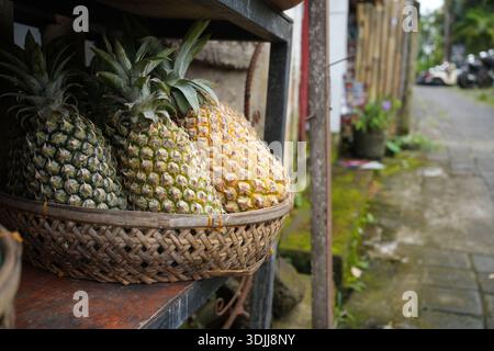 Frische Ananas in einem traditionellen handgewebten Korb an einem lokalen Straßenmarkt in Bali, Indonesien. Stockfoto