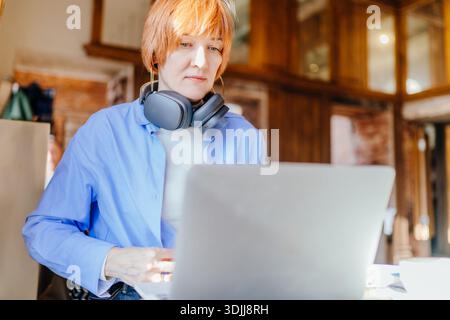 Fokussierte professionelle Frau analysiert Daten auf Laptop im Café Stockfoto