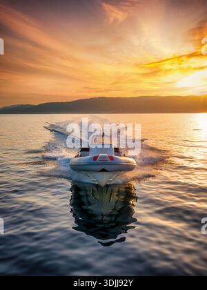 Aus der Vogelperspektive eines RIB-Motorbootes, das während eines wunderschönen Sonnenuntergangs über dem ruhigen Meer fährt Stockfoto
