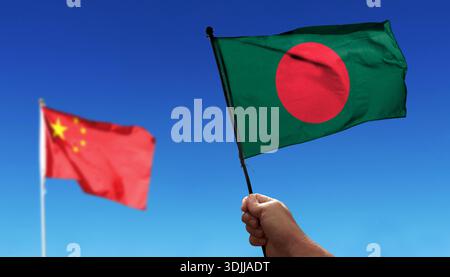 Bangladesch-Flagge winkt unter Wolken. Fliegen Sie in den Himmel. Foto der chinesischen Flagge mit absichtlich verschwommenem Hintergrund Stockfoto