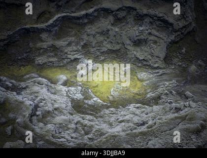 Aus der Vogelperspektive ein beeindruckender Kontrast zwischen dem kahlen, grauen Gelände und der lebhaften gelben heißen Quelle im Inneren, Flugir, Rangárþing ytra, Island. Stockfoto