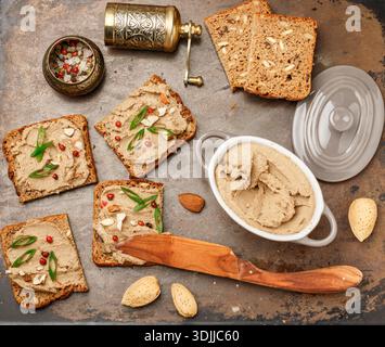 Frische hausgemachte Hühnerpastete (Ente, Gans, Kaninchen, Truthahn) mit Mandeln, rosa Pfeffer und grünen Zwiebeln auf Vollkornbrot mit Samen. Traditioneller gesunder Snack für Gourmets. Selektiver Fokus, Draufsicht Stockfoto