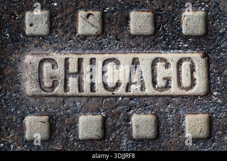 Detail des alten Mannlochdeckels in Chicago auf der Straße mit einer Struktur, die aus Eisen getragen und verwittert ist Stockfoto