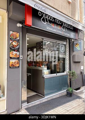 O Gyros Pou Ypereis Souvlaki Gyros Tzatziki zum Mitnehmen in Athen. Ausstellung griechischer Fast-Food-Artikel: Gyros, Souvlaki-Stick und griechischer Salat. Stockfoto