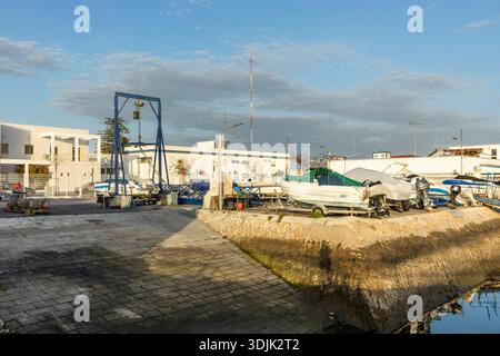 Ein kleiner Fischerhafen und Bootswartungsbereich in Olhão, Algarve, Portugal. Angelegte und trocken angedockte Fischerboote ruhen entlang eines von Steinen gesäumten Kanals darunter Stockfoto