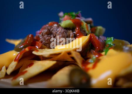 Köstliche Nachos mit herzhaftem Fleisch, cremiger Käsesauce, frischer Salsa und scharfem jalapeños Stockfoto