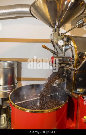 Der Kaffee wird von Hand in einer kleinen Trommelröstmaschine mit viel Erfahrung geröstet, in die die fertigen heißen Kaffeebohnen einfach ausgegossen werden Stockfoto