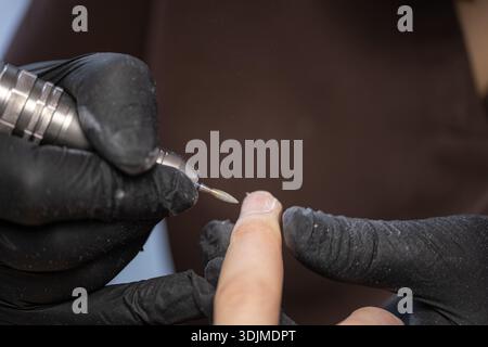 Professionelle elektrische Maniküre mit Nagelbohrer im Schönheitssalon Nahaufnahme Stockfoto