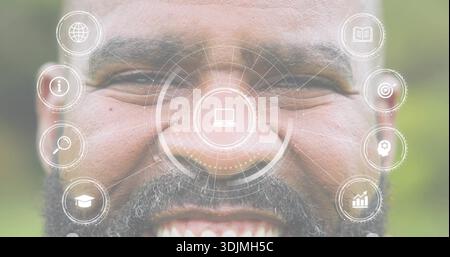 Ein lächelnder reifer Mann zeigt im Garten HUD-Überlagerungen auf dem Gesicht, zeigt Laptopsymbole und vertikale Symbole Stockfoto