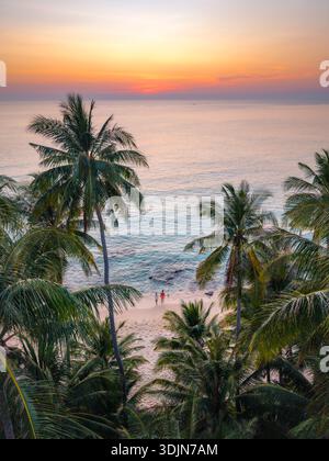 Erleben Sie die Schönheit des Takhian Strandes in Koh Kood, Thailand, während die Sonne untergeht und den Himmel in leuchtenden Farben malt, während Palmen sanft über dem Himmel schwingen Stockfoto