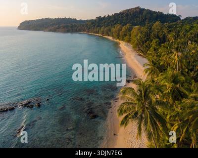 Erleben Sie die ruhige Schönheit des Takhian Beach in Koh Kood, Thailand. Goldener Sand trifft auf kristallklares Wasser unter einem pulsierenden Himmel, während Palmen schwanken Stockfoto