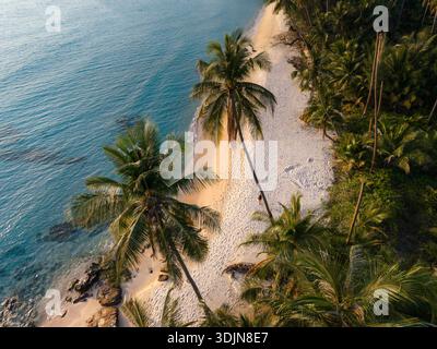 Erleben Sie die ruhige Schönheit des Takhian Beach auf Koh Kood, Thailand, wo sanfter Sand auf kristallklares Wasser trifft, umgeben von üppigen Palmen und a p Stockfoto