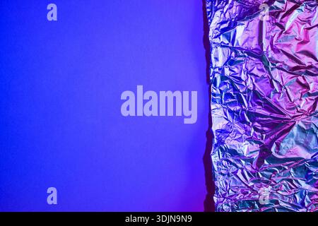 Zerknitterte Aluminiumfolie reflektiert abstraktes violettes und blaues Licht Stockfoto