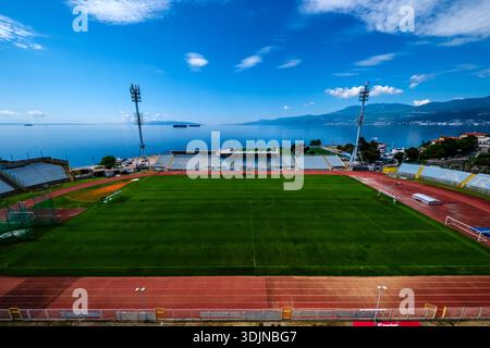 Kantrida-Stadion mit grünem Feld und Flutlichtern an der Adria. Učka Gebirge in der Ferne unter blauem Himmel. Stockfoto
