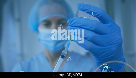 Entnahme von Medikamenten mit Spritze aus der Durchstechflasche mit blauem Handschuh in der Klinik mit Maske Stockfoto