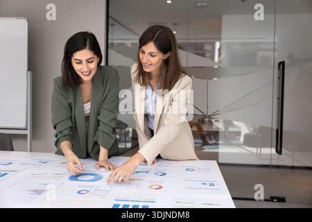 Zwei Geschäftsfrauen, die analytische Diagramme auf dem Tisch überprüfen Stockfoto