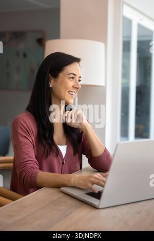 Lächelnde Frau am Laptop zu Hause arbeiten Stockfoto