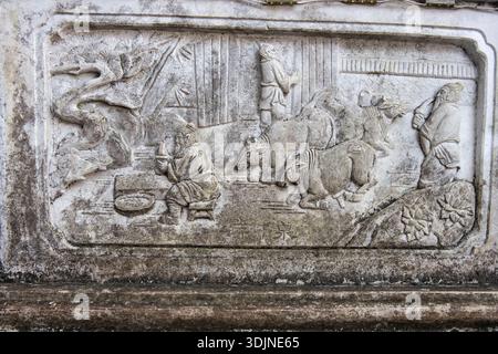 Steinschnitzerei über die Geschichte der kindlichen Rinderquelle im Xishan Mountain, Kunming – ein Metzger plante, eine Kuh zu schlachten, aber ihr Kalb weinte. Stockfoto
