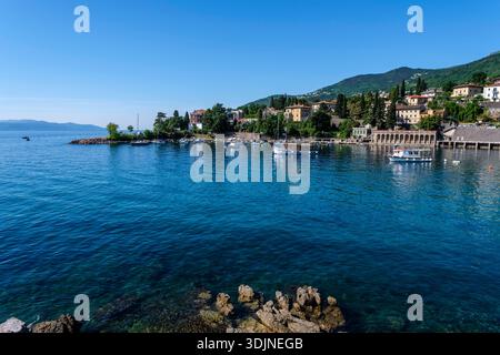 Boote liegen im Hafen von IKA. Küstengebäude und üppige grüne Hügel unter einem klaren blauen Himmel in der Ferne. IKA Istrien Kroatien FB 2025 0697 Stockfoto
