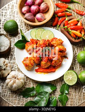 Köstliche scharfe Fleischbällchen oder Fischbällchen, überzogen mit leuchtender roter Chili-Sauce und garniert mit frischen Limettenscheiben und aromatischen Kaffir-Limettenblättern, Beauti Stockfoto
