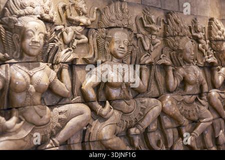 Detaillierte Steinschnitzereien mit Relief von Apsara-Tänzern in einem alten Khmer-Tempel in Kambodscha. Anmutige Figuren zeigen heitere Ausdrücke, die TRA darstellen Stockfoto