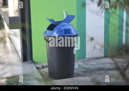 Blauer und schwarzer Kunststoffmüll für die öffentliche Müllentsorgung, der im Freien auf Betonboden steht. Dieser Abfallbehälter trägt zur Erhaltung von Urban cleanline bei Stockfoto