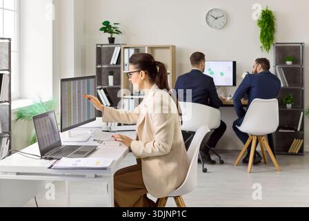 Konzentrierter Prüfer, der Finanzdaten auf zwei Monitoren in modernen Büros überprüft Stockfoto