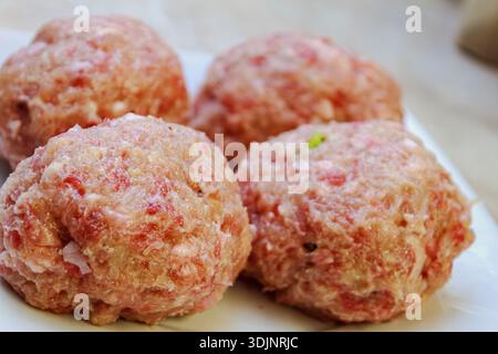 Vier rohe runde Fleischkoteletts oder Fleischbällchen auf einer Oberfläche. Zubereitung von hausgemachten Fleischgerichten. Stockfoto