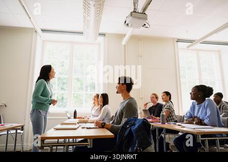 Eine Professorin unterrichtet Erwachsene Studenten, die im Klassenzimmer am College sitzen Stockfoto