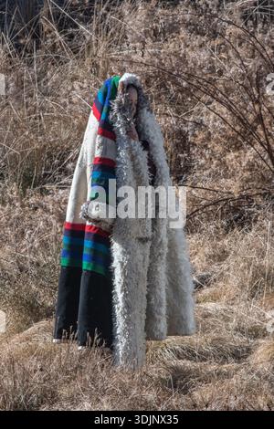 Eine chinesin in einem schweren traditionellen Mantel steht im Winter auf einem Feld. Sichuan, China. Stockfoto