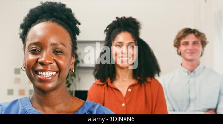 Happy Trio in Office: Lächelnde Kollegen bereit für Zusammenarbeit und Innovation Stockfoto