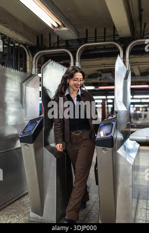 Eine junge Geschäftsfrau, die in New york am U-Bahn-Drehkreuz einsteigt Stockfoto