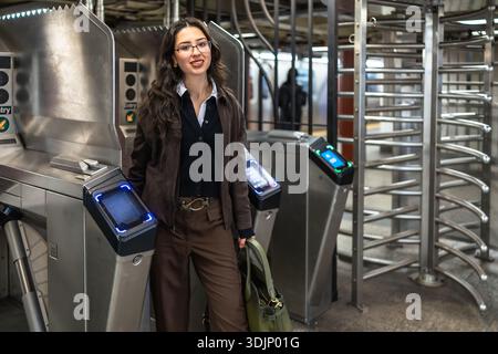 Eine junge Geschäftsfrau, die am U-Bahn-Drehkreuz in New york steht Stockfoto