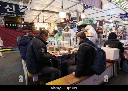 Seoul, Südkorea: Einheimische Männer essen während der Wintersaison heiße Suppe am traditionellen Marktstand Stockfoto
