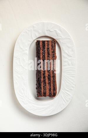 Schokoladenschicht-Kuchenscheibe auf weißem Teller Stockfoto