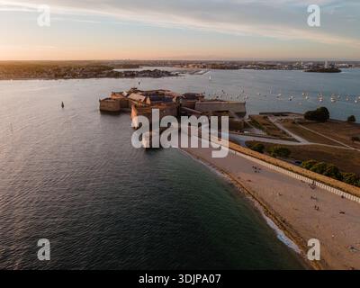 Blick aus der Vogelperspektive auf die Citadelle de Port-Louis in der Bretagne, Frankreich, die im warmen goldenen Stundenlicht des Sonnenuntergangs leuchtet und ihre Befestigungsanlagen hervorhebt Stockfoto