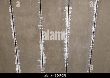 Deckenplatten aus Fertigbeton mit rauer Textur und unordentlicher weißer Dichtmasse auf Fugen, die unfertige Details aus Industriebau zeigen Stockfoto