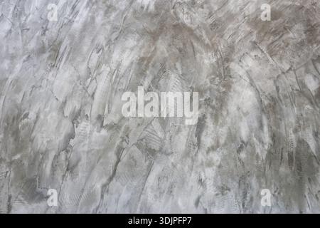 Die graue polierte Betonwandstruktur mit einer Oberfläche mit verstörtem und grundigem Muster schafft einen rauen industriellen Hintergrund und abstrakte Details für modernes Design Stockfoto