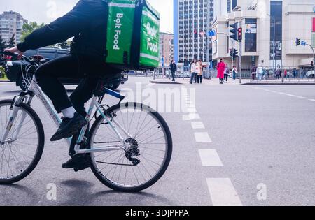 Kiew, Ukraine - 6. Mai 2023 : Bolt Food Kurier auf einem Fahrrad durch die belebte Kiewer Straße, durch Fußgänger und Verkehr, um Bestellungen zu liefern Stockfoto