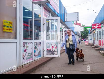 Kiew, Ukraine - 6. Mai 2023 : Seniorin, die mit einem Einkaufswagen an einem Marktgang entlang geht und das tägliche Straßenleben in Kiew, Ukraine, zeigt Stockfoto