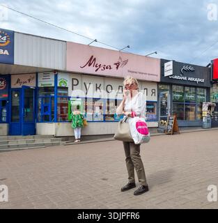 Kiew, Ukraine - 6. Mai 2023 : Frau, die auf dem Bürgersteig der Stadt steht und auf dem Handy spricht, während Fußgänger Geldautomaten benutzen und Geschäfte in Kiew geschäftig sind Stockfoto