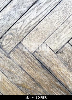 Nahaufnahme des Holzparkettbodens mit Fischgrätenmuster, das die natürliche Körnung und Textur in einer hellbraunen Farbpalette unterstreicht Stockfoto