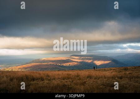Zwei Wanderer stehen auf einem Kamm in Bannau Brycheiniog und blicken zur goldenen Stunde nach Norden in Richtung Llangynidr Stockfoto
